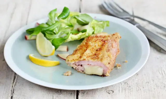 Un délicieux cordon bleu croustillant, garni de fromage fondant, servi avec une salade fraîche et des quartiers de citron.