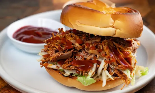 Burger généreux garni d'effiloché de porc savoureux, de salade croquante et nappé de sauce barbecue. Un délice !
