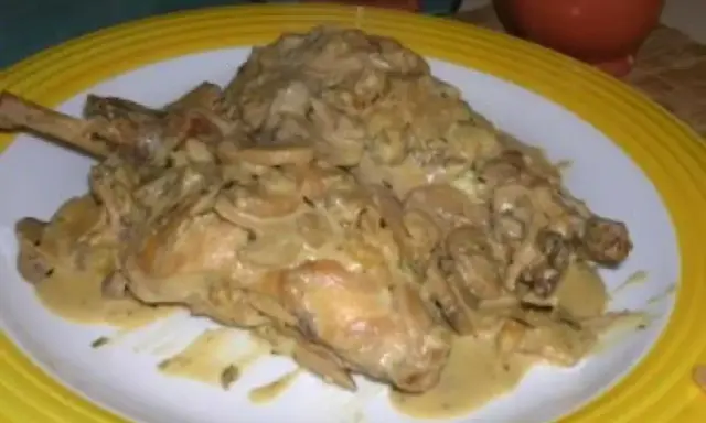 Un plat de lapin à la moutarde, crémeux et savoureux, servi sur une assiette blanche bordée de jaune.
