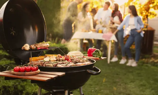 Un barbecue ouvert crépite, cuisant viandes et légumes sous un soleil doré. Des amis discutent joyeusement en arrière-plan, profitant d'un moment convivial.