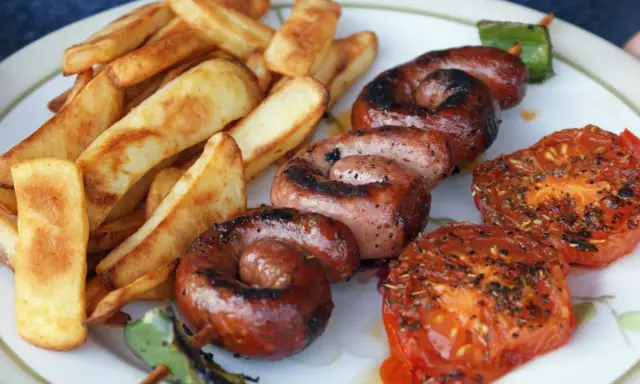 Assiette de saucisse à la plancha, frites dorées et tomates grillées. Un délice estival !