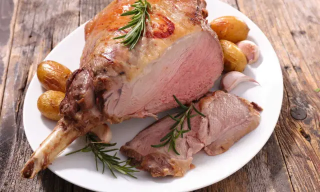 Gigot d'agneau rôti, tendre et juteux, accompagné de pommes de terre et d'ail. Un plat parfait pour un gigot pour 10 personnes.