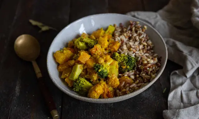 Un bol de riz et un curry de légumes coloré avec du brocoli, de la courge et des pois chiches.