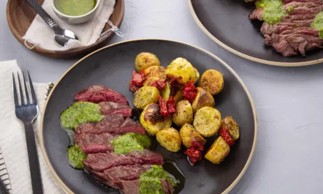 Tranches de bœuf juteux nappées de pesto, accompagnées de pommes de terre rôties et de tomates séchées. Quelle viande avec du pesto, un délice !