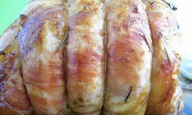 Un rôti de veau savoureux, enveloppé de lard et parsemé de romarin, prêt à être dégusté.