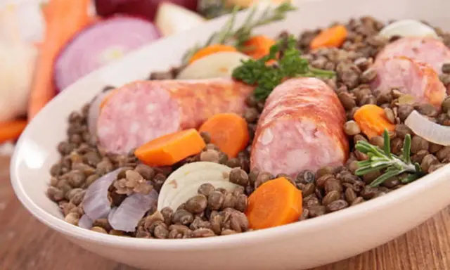 Un plat réconfortant de saucisses lentilles, garni de carottes, oignons et romarin.