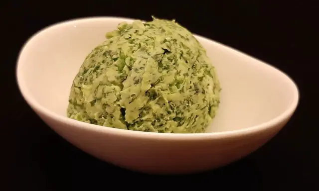Une boule de beurre à l'ail et au persil dans un bol blanc. Parfait pour accompagner vos plats !