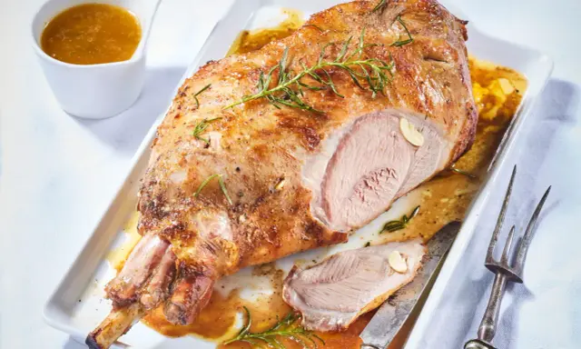 Gigot d'agneau pour 6 personnes, rôti à la perfection, servi avec sa sauce et garni de romarin.