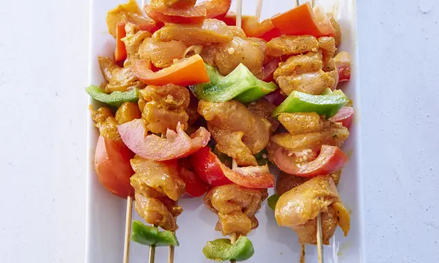 Brochettes de poulet marinées, tomates et poivrons verts, prêtes pour une recette brochette poulet barbecue.