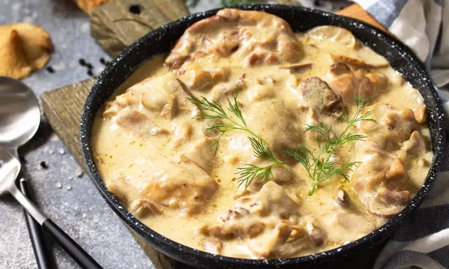 Poulet de Bresse à la crème, servi dans une poêle, garni d'aneth.