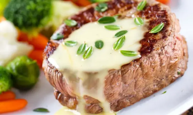Un steak tendre nappé d'une onctueuse sauce béarnaise, accompagné de légumes verts et de carottes.