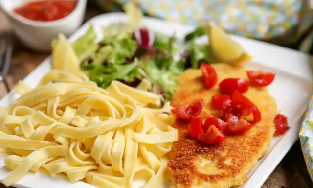 Une assiette de pâtes fraîches, une escalope milanaise dorée garnie de tomates cerises, et une salade verte. Un délice !