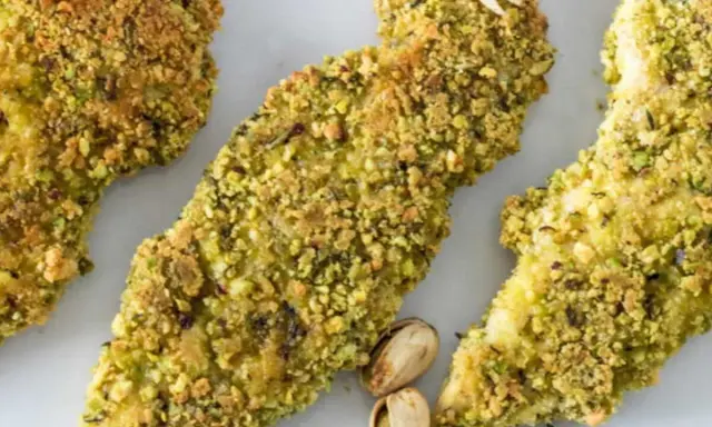 Trois tendres morceaux de poulet pistache, croustillants et dorés, sont présentés sur fond blanc.