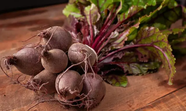 Un bouquet de betteraves fraîches, prêtes pour une délicieuse recette betterave. Leurs feuilles vertes et leurs racines pourpres promettent saveur et couleur.