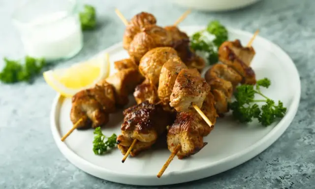 Brochettes de poulet citronnées, dorées et juteuses, garnies de persil frais et d'un quartier de citron. Un délice à savourer !