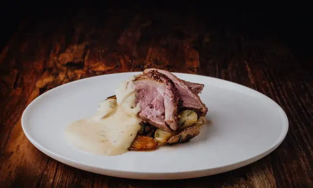 Tranches de gigot d'agneau rosées, nappées d'une sauce chasseur onctueuse, servies sur des pommes de terre rôties. Un délice pour les gourmands.