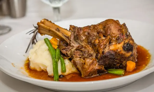 Une souris d'agneau braisée, servie avec une purée onctueuse, des haricots verts croquants et des dés de carottes, le tout nappé d'une sauce savoureuse.