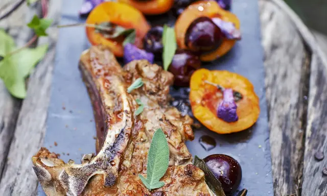 Délicieuse côte de veau barbecue, servie avec des abricots rôtis et des cerises, garnie de sauge fraîche.