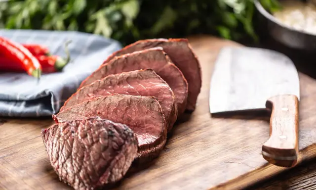 Tranches de rôti de bœuf, poivrons rouges et couteau de boucher. Que faire avec ce reste de viande cuite ?