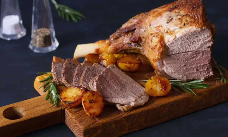 Gigot d'agneau rôti, pommes de terre et romarin sur une planche en bois. Un plat parfait pour la viande pour Pâques.