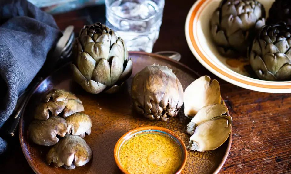 Artichauts prêts à être dégustés, accompagnés d'une sauce savoureuse. Une idée pour une recette artichaut simple et délicieuse.