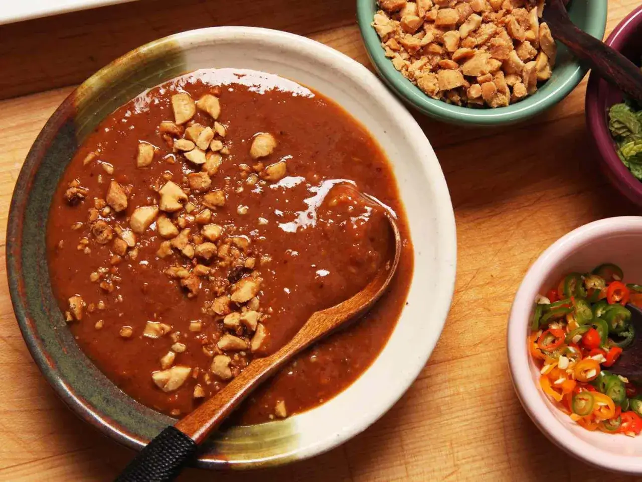 Sauce &agrave; viande onctueuse, garnie de cacahu&egrave;tes concass&eacute;es, pr&ecirc;te &agrave; &ecirc;tre servie avec des piments et des herbes fra&icirc;ches.