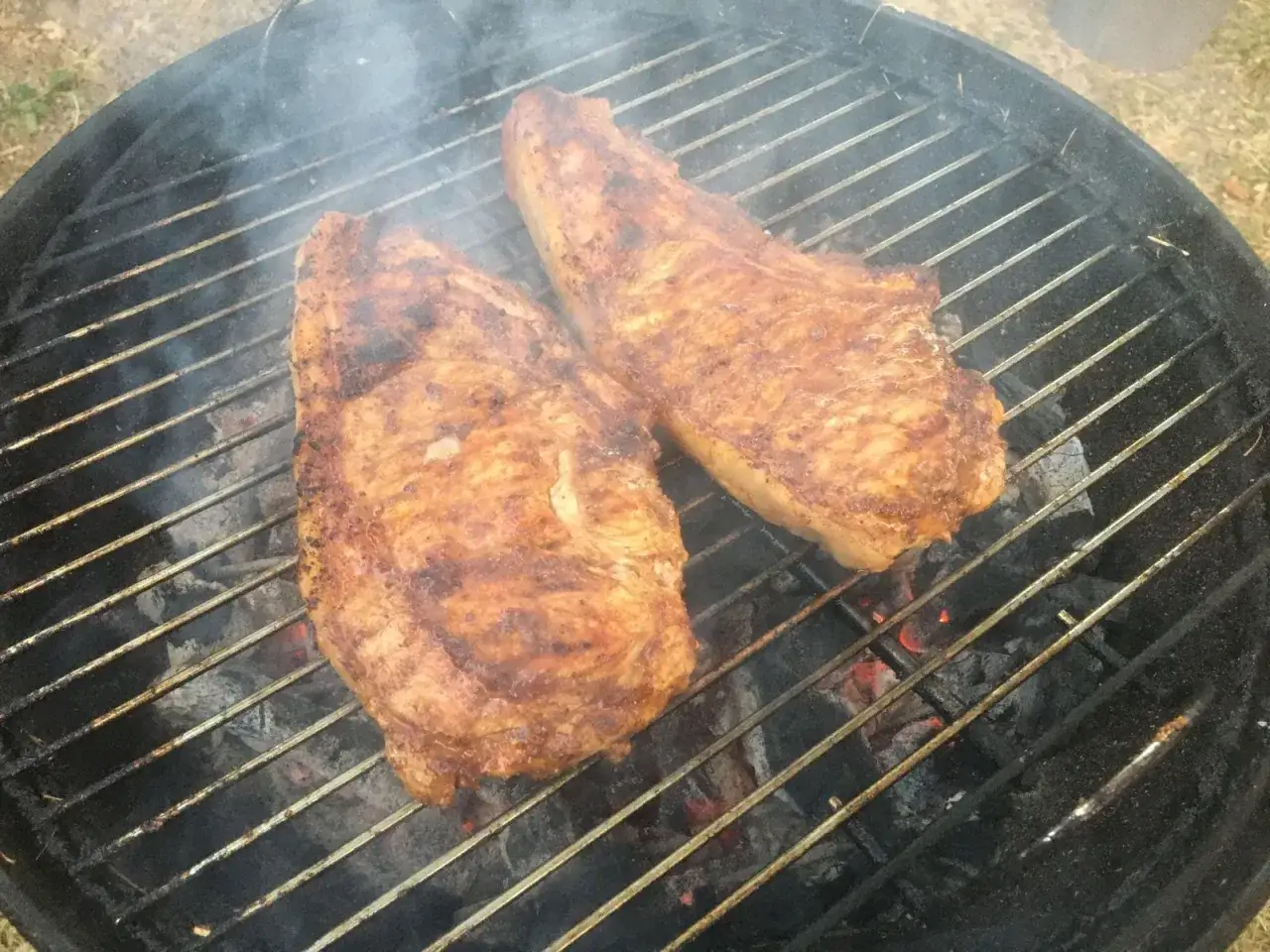 Deux belles côtes de veau barbecue grésillent sur le grill, dégageant une fumée alléchante.