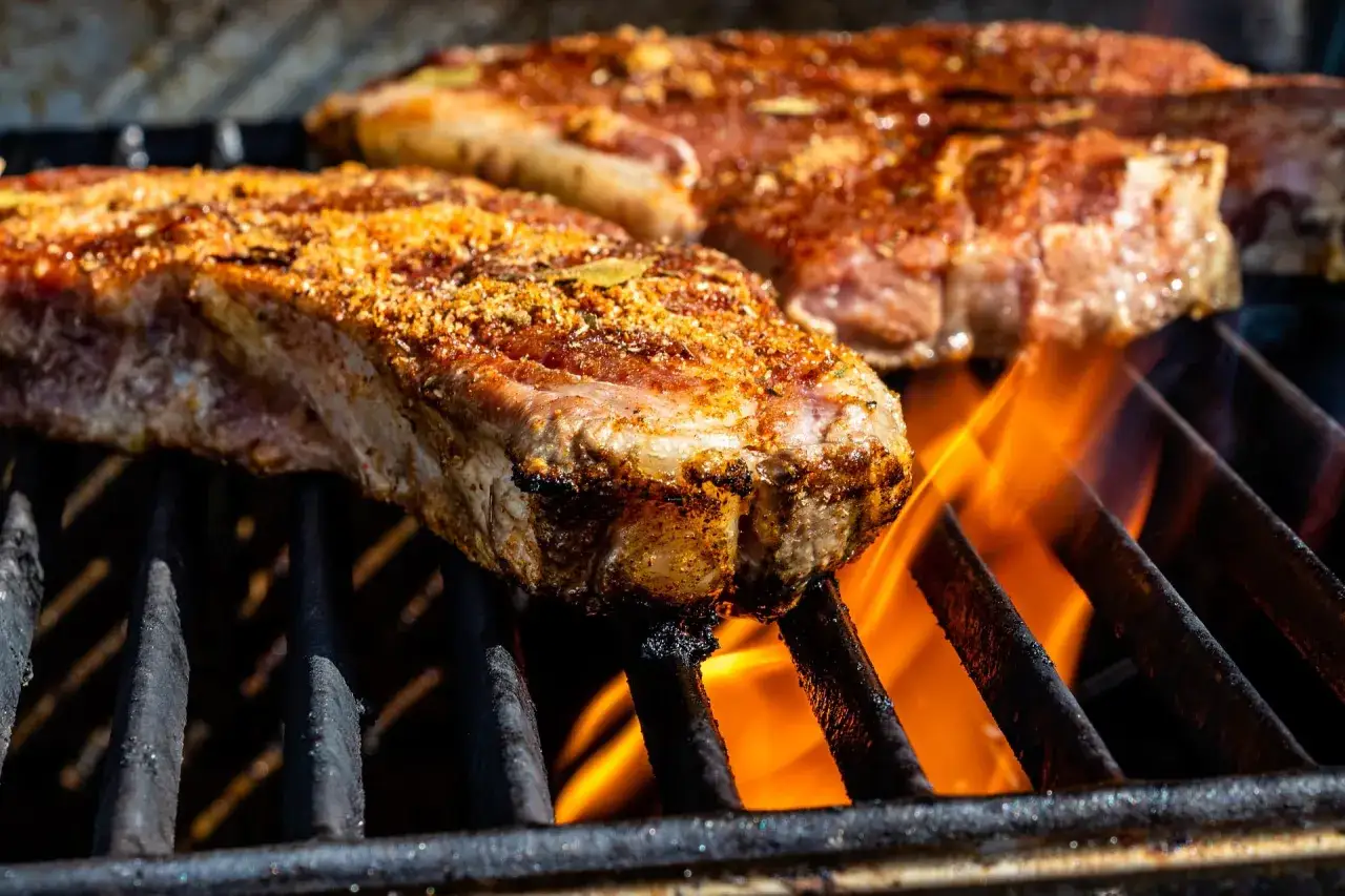Une succulente entrecôte de bœuf, assaisonnée et grillée à la perfection, avec des flammes vives léchant la grille.