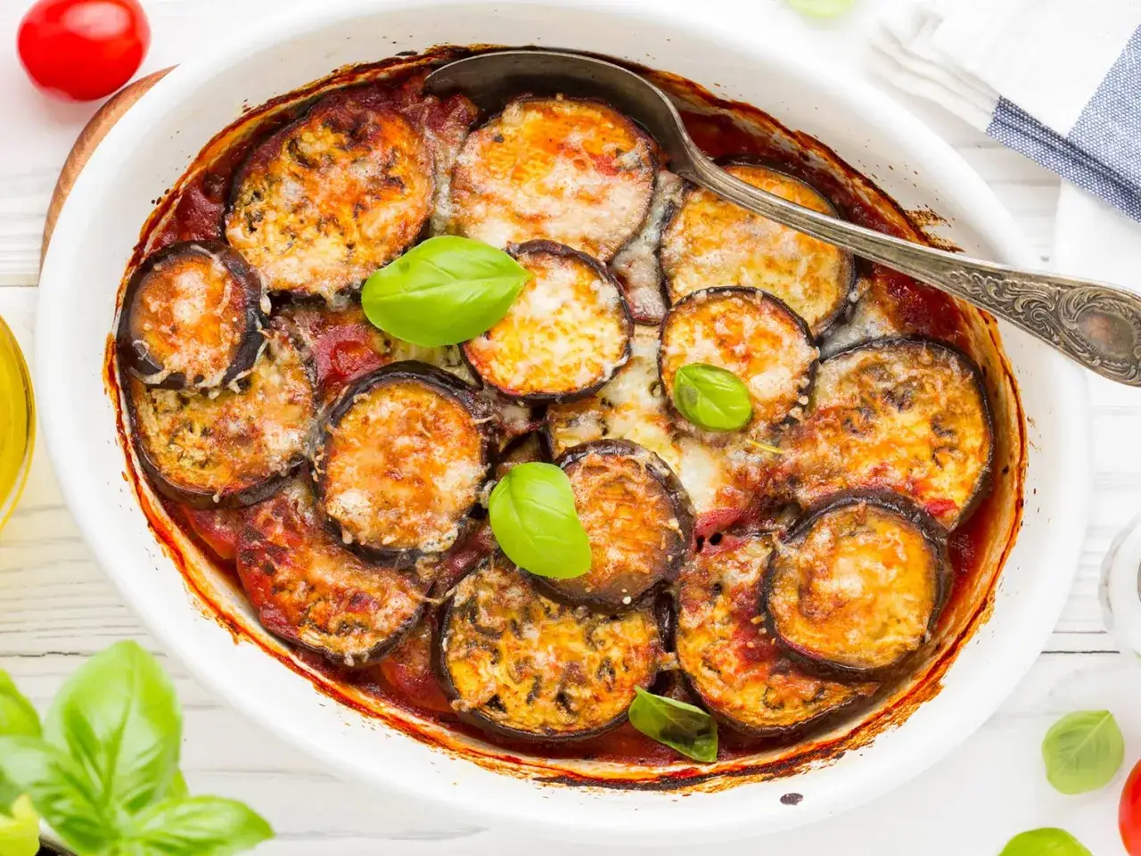Un plat de moussaka rapide, gratiné et savoureux, avec des aubergines, de la sauce tomate et du fromage fondant, garni de feuilles de basilic frais.