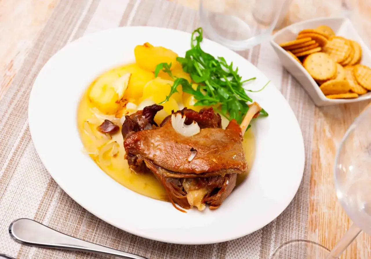 Une délicieuse cuisse de canard confite, servie avec des pommes de terre rôties et une touche de roquette fraîche.