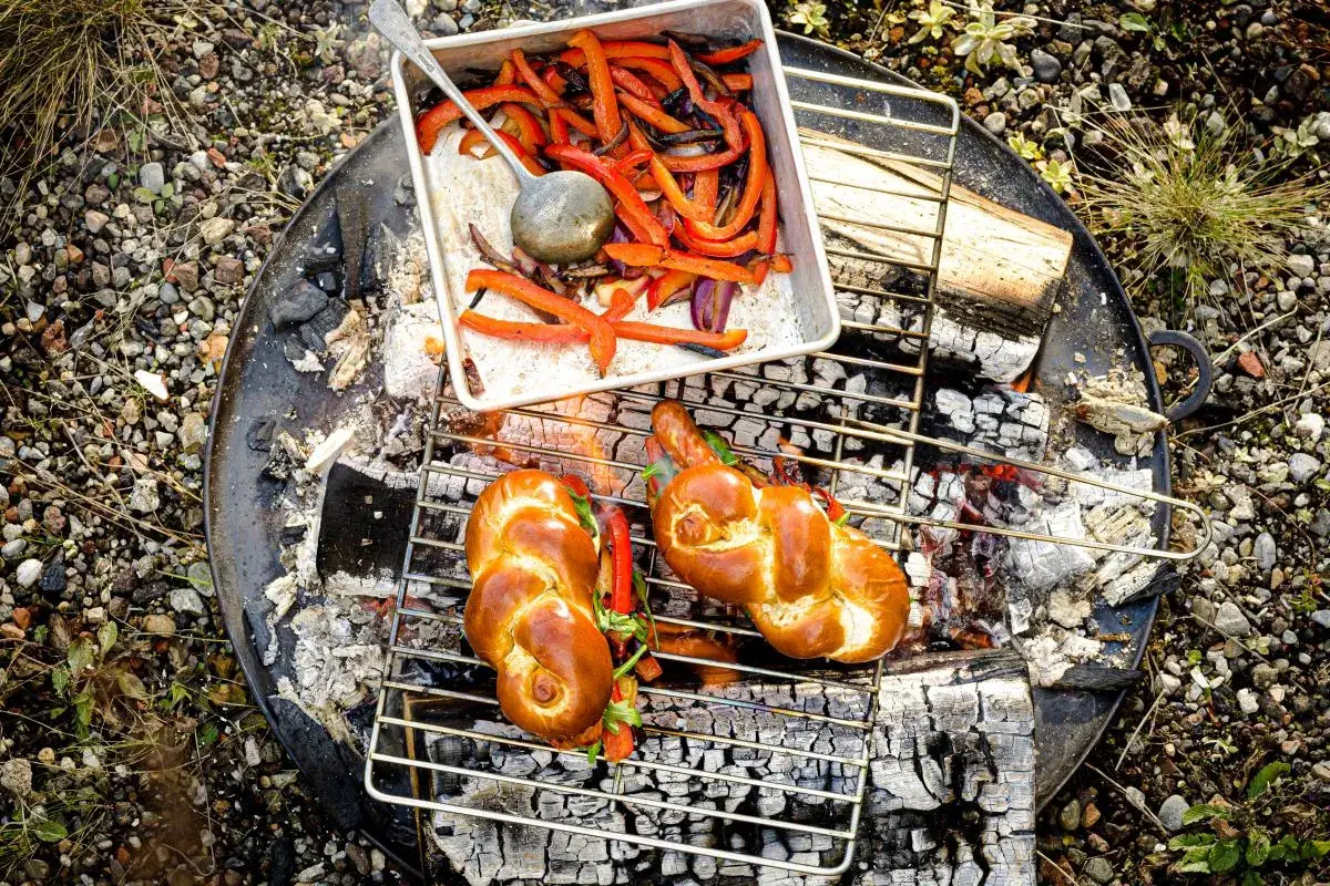 Deux pains tressés dorés prêts pour un barbecue hot dog, avec des poivrons grillés à côté.