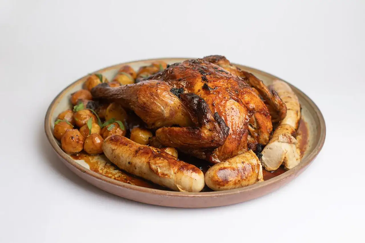 Un plat de fête : poulet rôti doré, pommes de terre grenaille et saucisses, une délicieuse farce poulet avec abats.