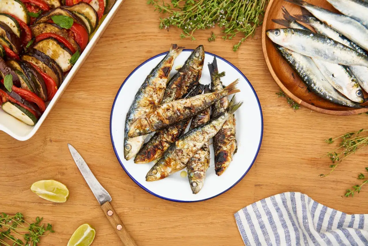 Poisson au barbecue grillé, servi sur une assiette blanche, avec des herbes fraîches et des quartiers de citron vert.