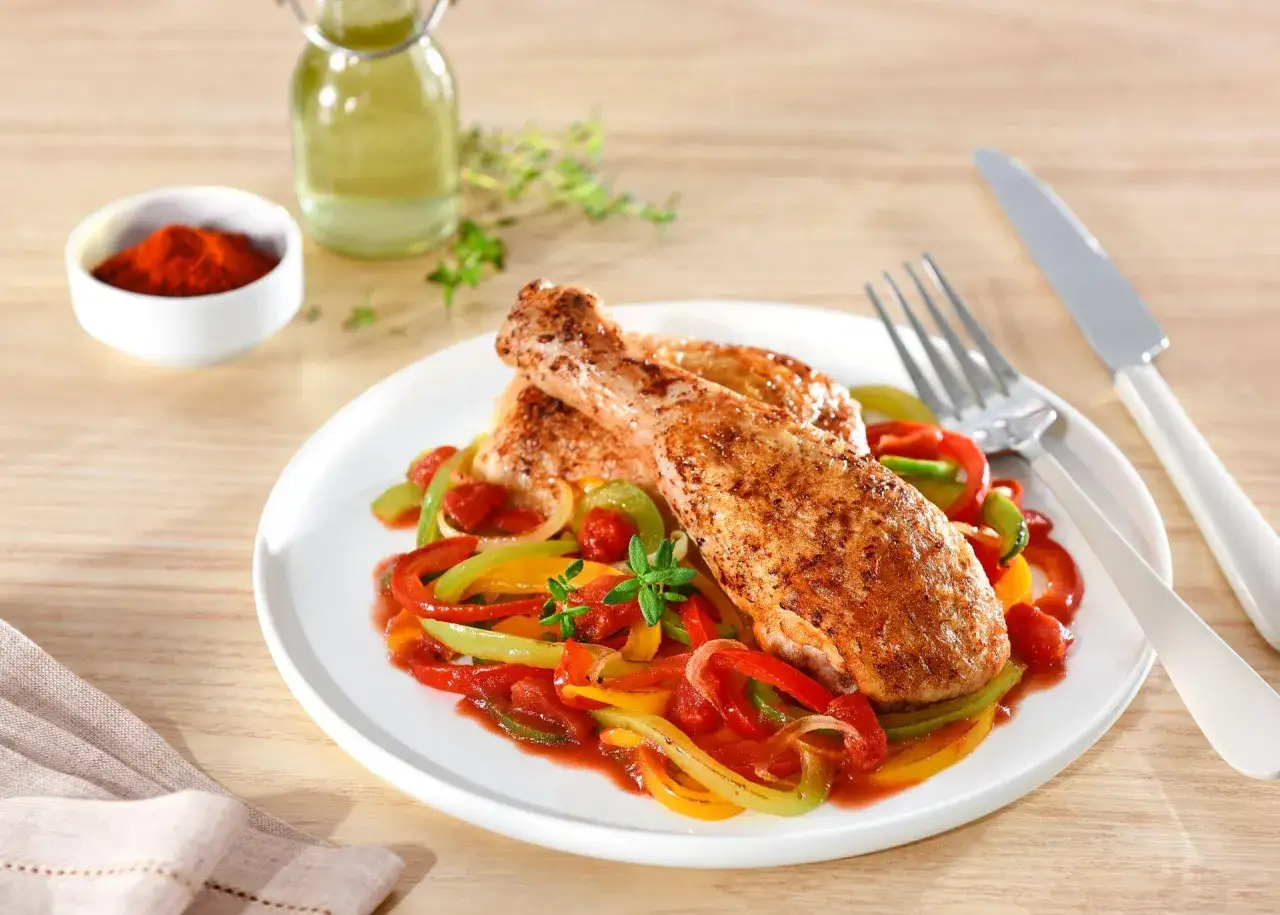 Poulet basquaise cookeo : des cuisses de poulet savoureuses sur un lit de poivrons color&eacute;s et de tomates, pr&ecirc;t &agrave; &ecirc;tre d&eacute;gust&eacute;.