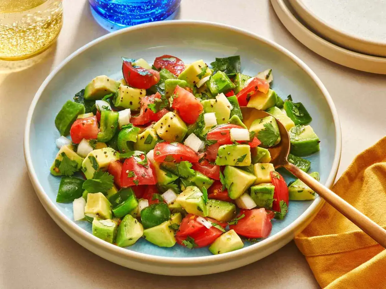 Salade fraîche et colorée, parfaite pour une recette avocat. Des dés d'avocat, tomates, poivrons verts et oignons, assaisonnés et parsemés de coriandre.