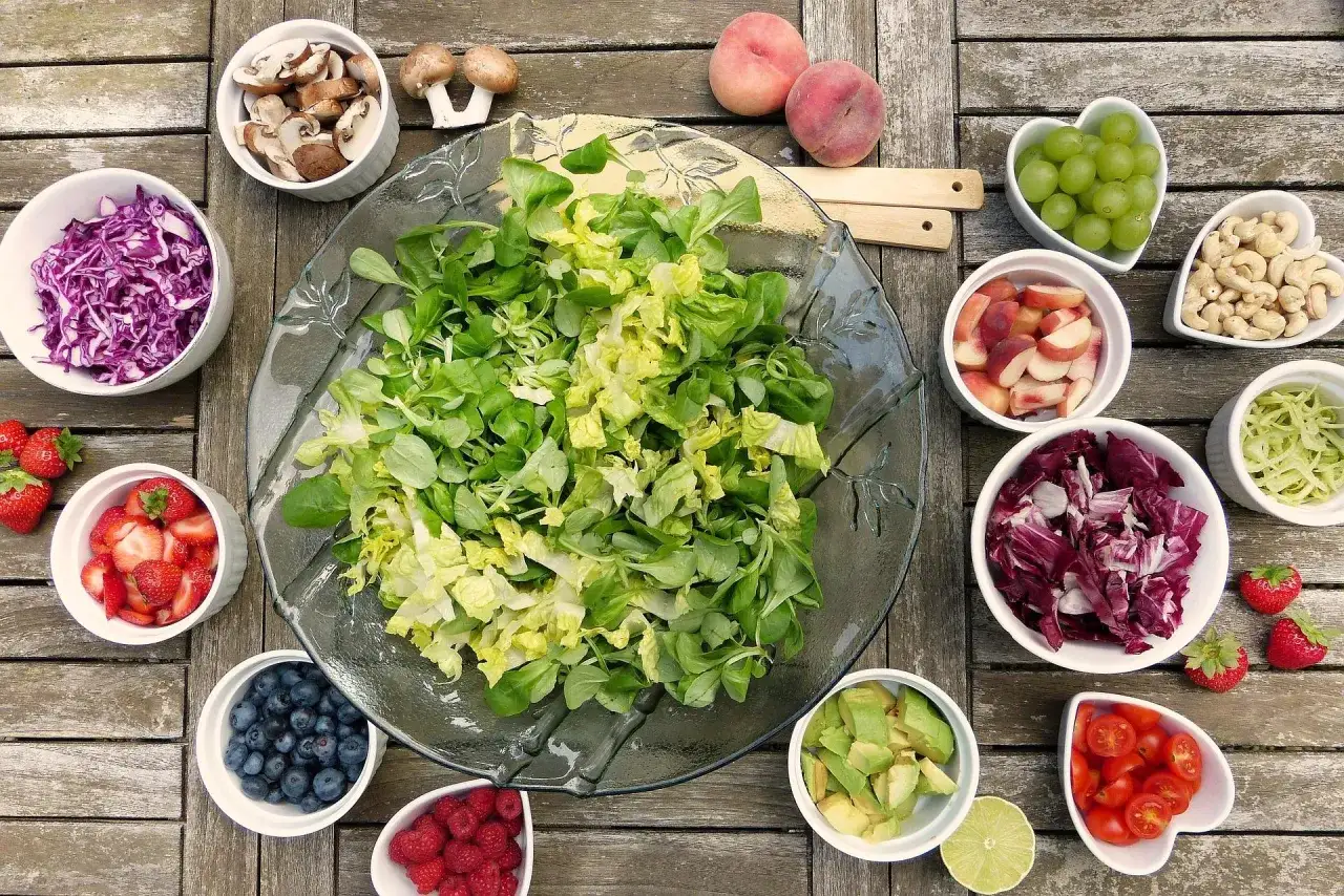 Un assortiment coloré de fruits et légumes frais, parfait pour un accompagnement barbecue. Salade verte, fraises, myrtilles, framboises, pêches, raisins, avocats, tomates, chou rouge, radicchio, champignons et noix de cajou.