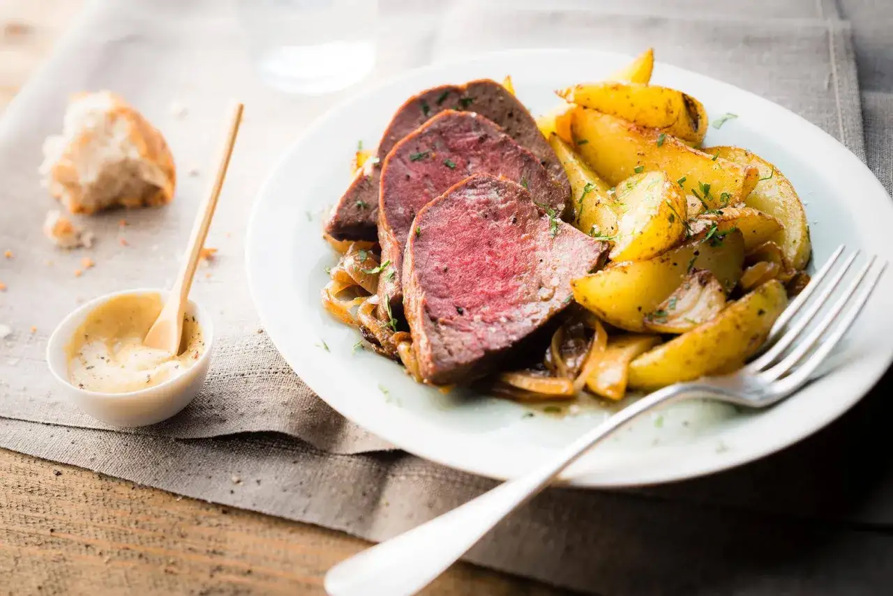 Tranches de roti de boeuf tendre, accompagnées de pommes de terre rôties et d'une sauce moutarde crémeuse.