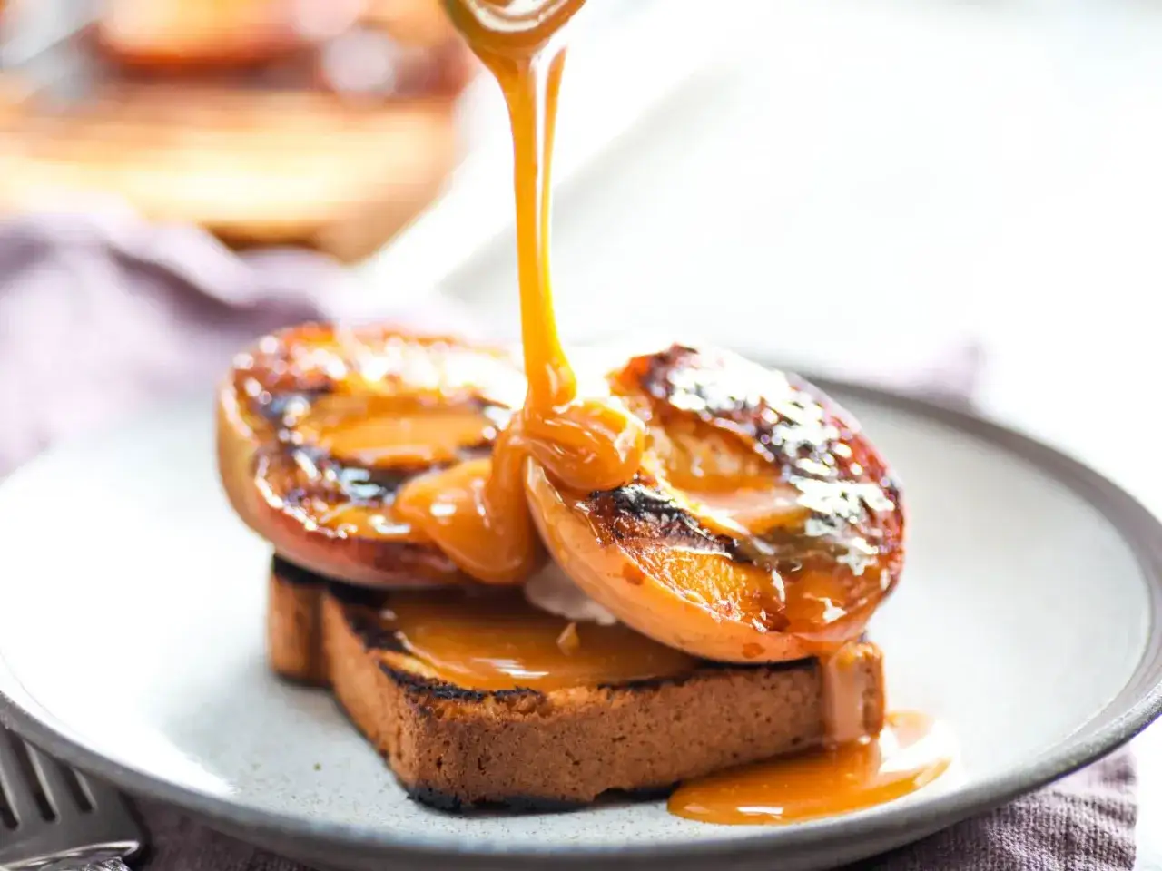 Délicieux dessert plancha : pêches grillées et leur sauce caramel coulante sur une tranche de pain brioché.