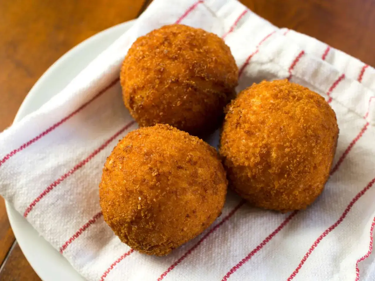 Trois arancini dor&eacute;s et croustillants, pr&ecirc;ts &agrave; &ecirc;tre d&eacute;gust&eacute;s. Une recette simple pour un plaisir garanti.