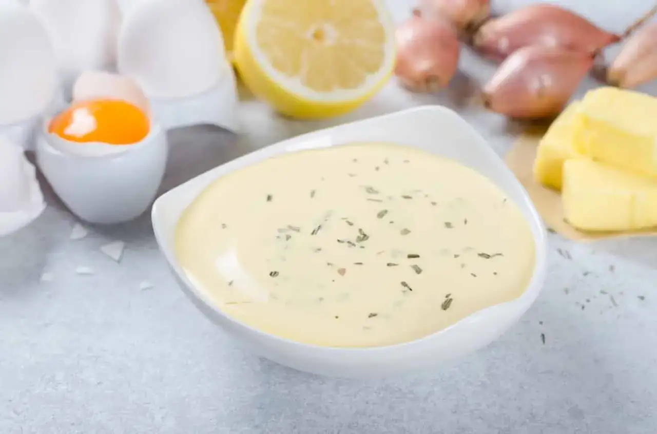 Sauce béarnaise onctueuse, prête à être dégustée avec ses ingrédients : œufs, citron, échalotes et beurre.