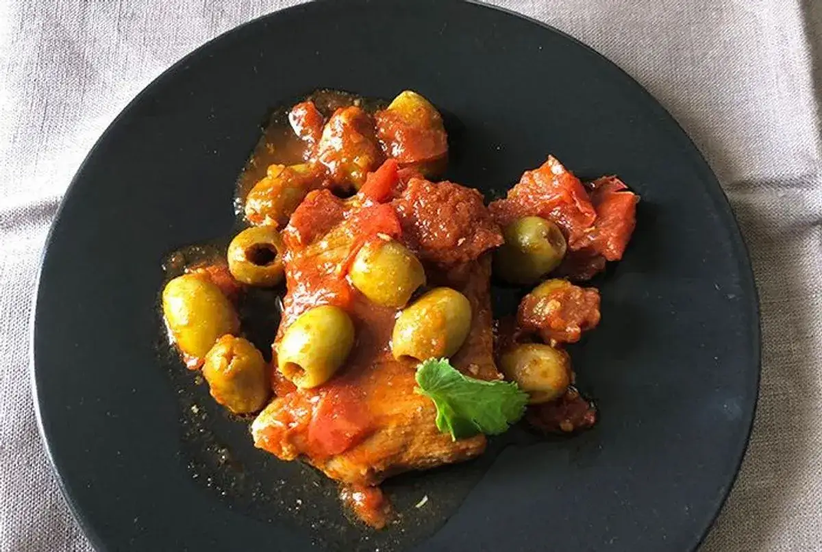 Un savoureux sauté de veau aux olives, baignant dans une sauce tomate parfumée. Une assiette appétissante prête à être dégustée.