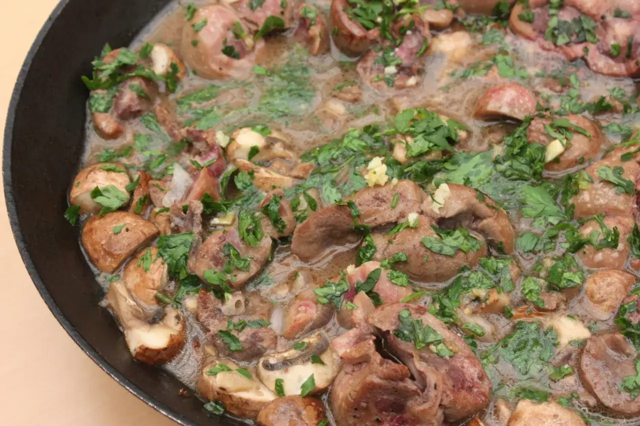 Délicieux rognon de veau mijoté avec des champignons et du persil frais dans une poêle.