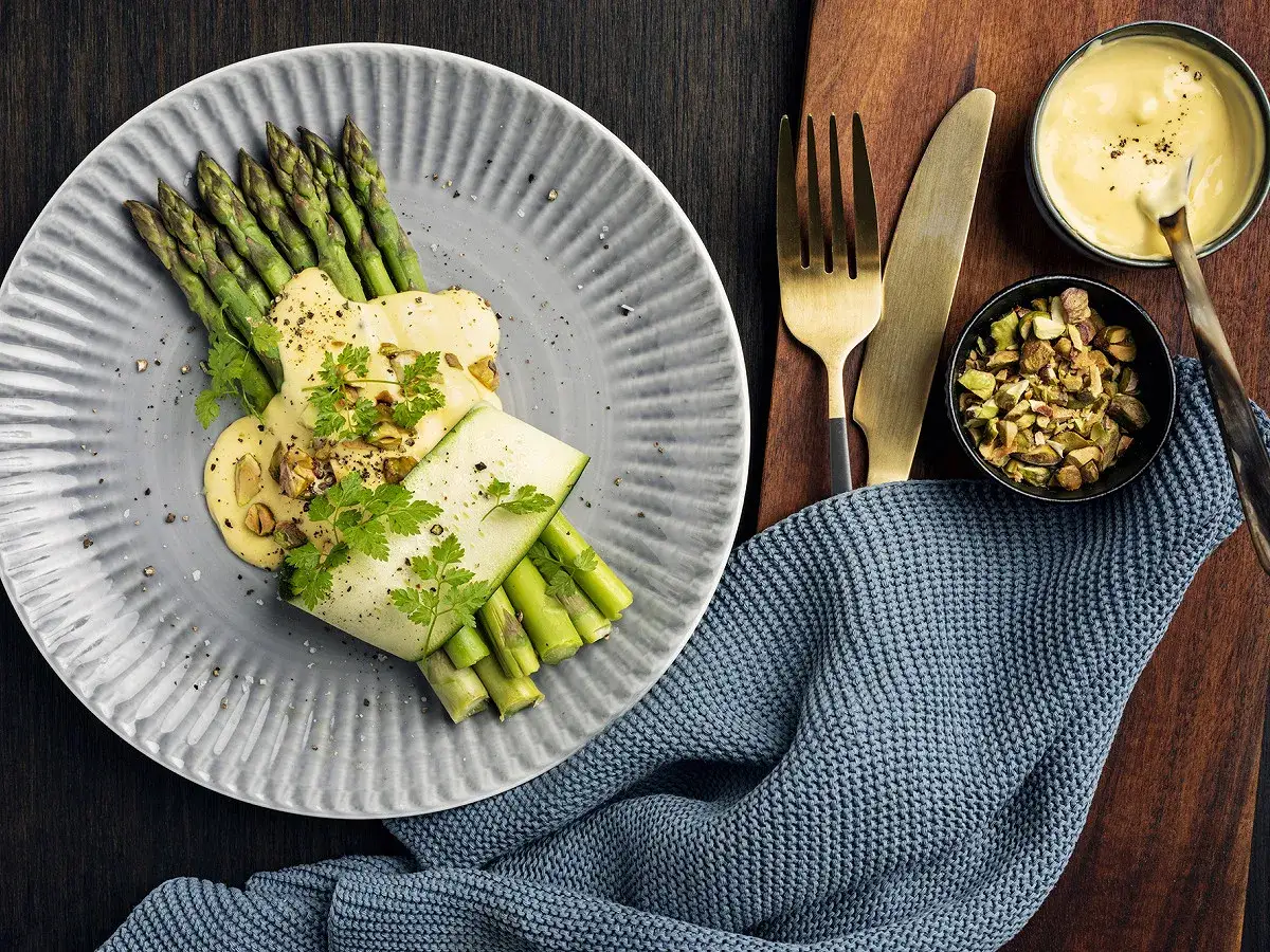 Asperges vertes nappées d'une sauce onctueuse, garnies de pistaches concassées et de persil frais. Une délicieuse mousseline asperge prête à être dégustée.