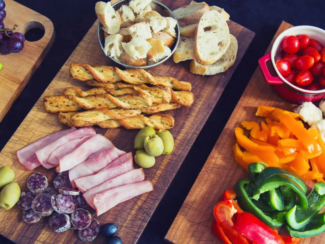 Quel accompagnement fondue viande : pain, charcuterie, olives, tomates cerises et poivrons colorés.
