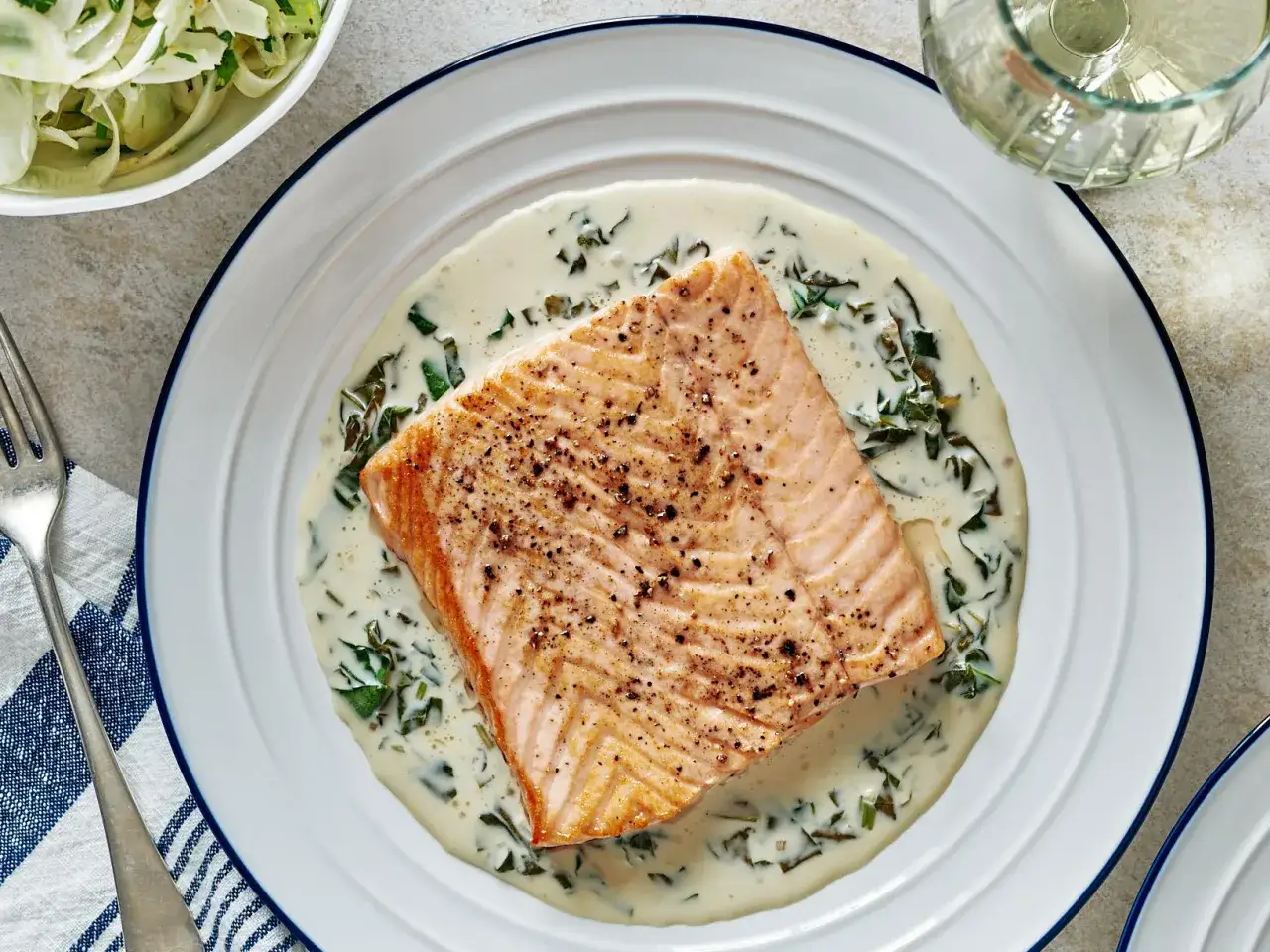 Filet de saumon poêlé nappé d'une onctueuse sauce à l'oseille, servi avec une salade de fenouil.