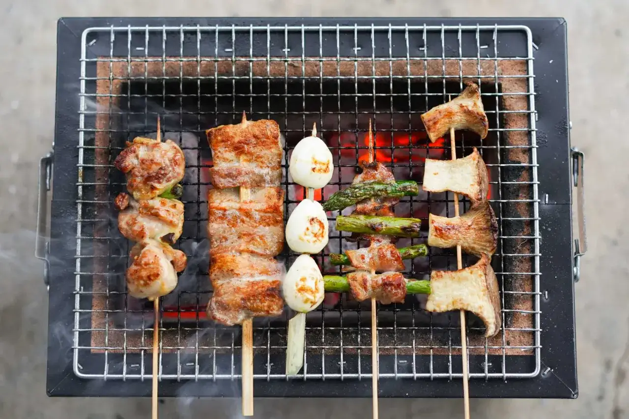Brochettes yakitori de poulet, porc, asperges et champignons, grillées à la perfection sur un barbecue.