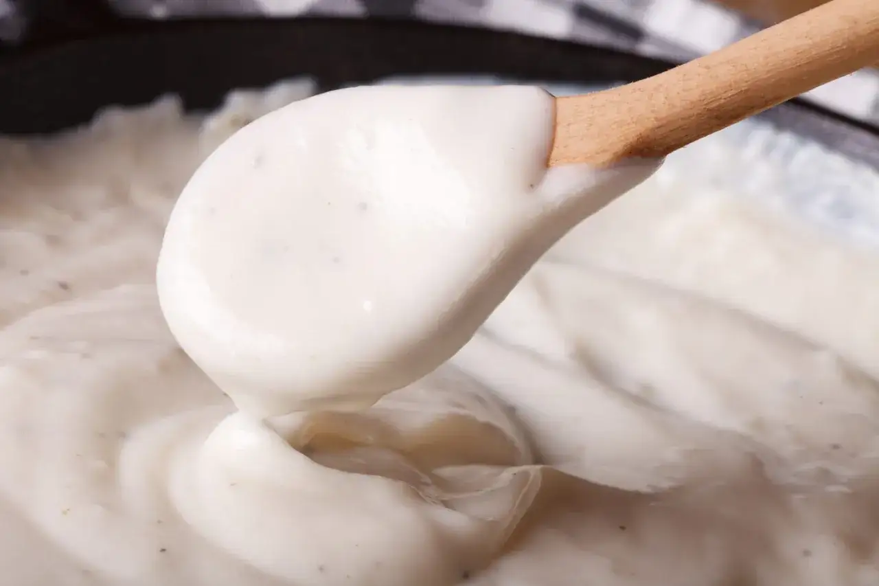Cuill&egrave;re en bois pr&eacute;levant une sauce onctueuse, une b&eacute;chamel sans beurre cr&eacute;meuse et savoureuse, parfaite pour vos plats.