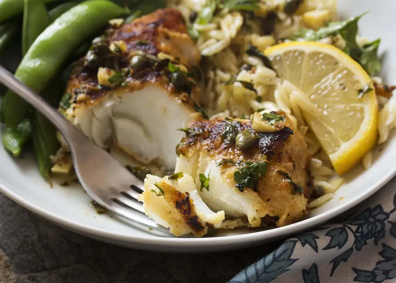 Morue grillée savoureuse, servie avec des pois gourmands, du riz orzo et une tranche de citron. Un délice !