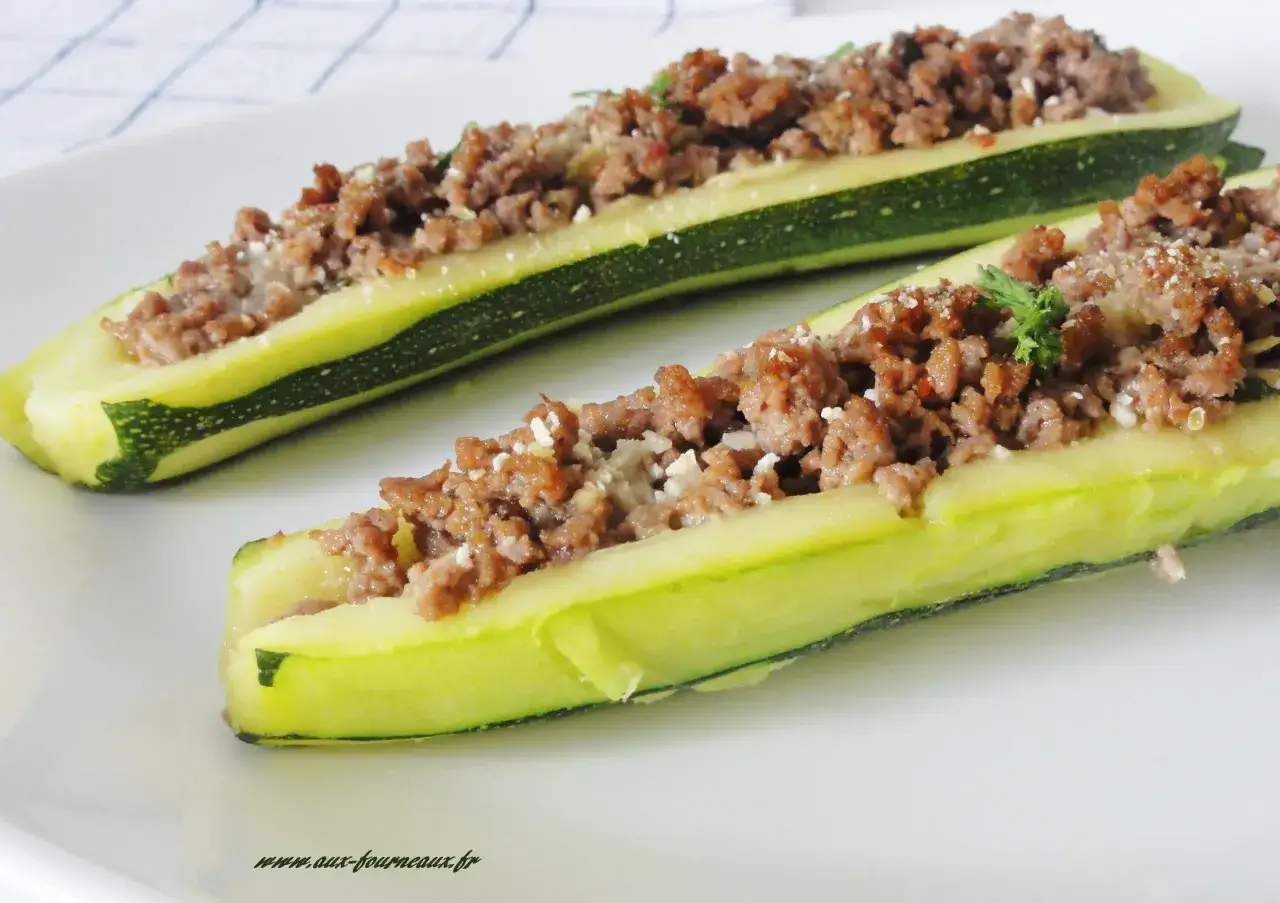 Deux courgettes fendues et garnies d'une farce savoureuse à la viande hachée, saupoudrées de fromage râpé. Un délice de courgette farcie prêt à être dégusté.