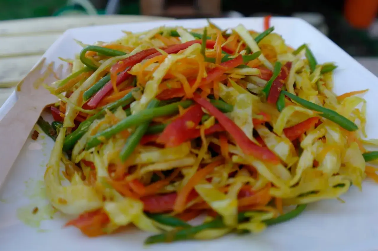 Un achard de l&eacute;gumes color&eacute;, m&eacute;lange de chou, carottes, poivrons et haricots verts, pr&ecirc;t &agrave; &ecirc;tre d&eacute;gust&eacute; avec une fourchette en bois.